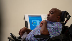 Ricky sits in front of a ballot machine.