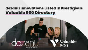 dozanü team members working around a table. dozanü logo and Valuable 500 logos shown in white on bottom. Bold black text on top shows: "dozanü innovations Listed in Prestigious Valuable 500 Directory"