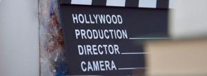 A close-up of a black and white Hollywood clapperboard with blank spaces for production, director, and camera info.